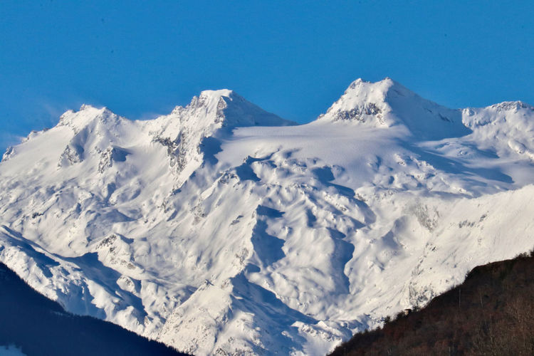 Scenic view of snowcapped mountains against blue sky