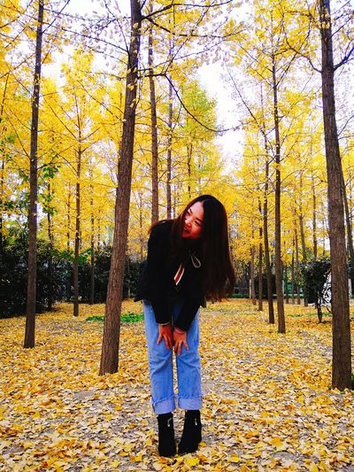 Young woman standing by yellow autumn tree