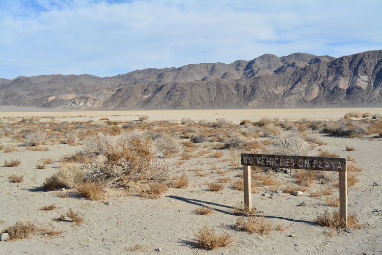 Information sign on desert against sky