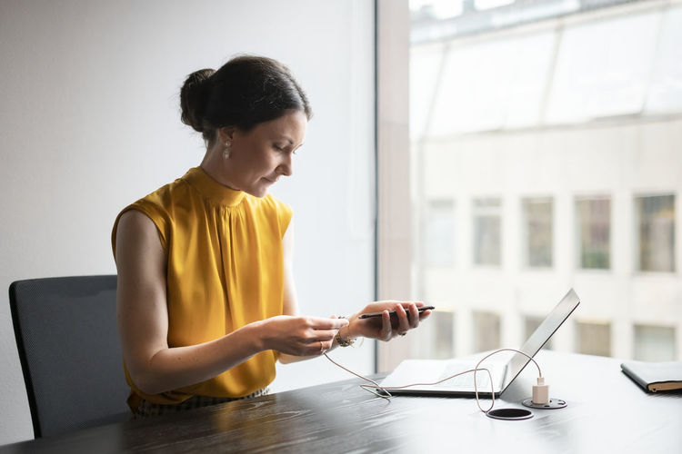 Woman using phone while sitting on table
