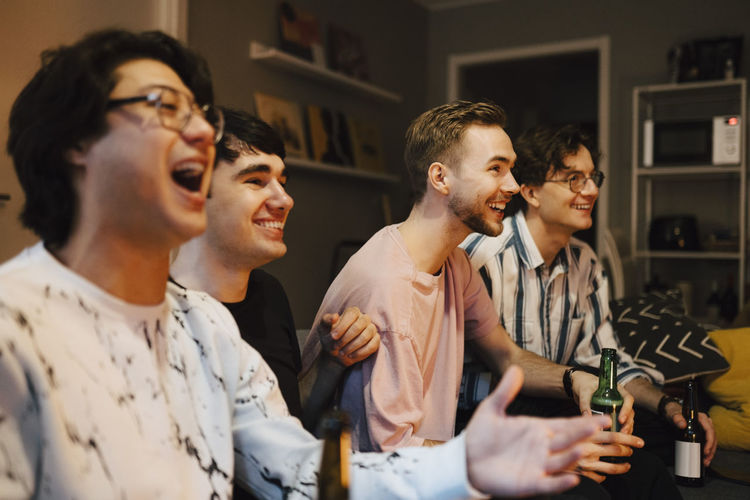 Excited multi-ethnic male friends watching sports at home