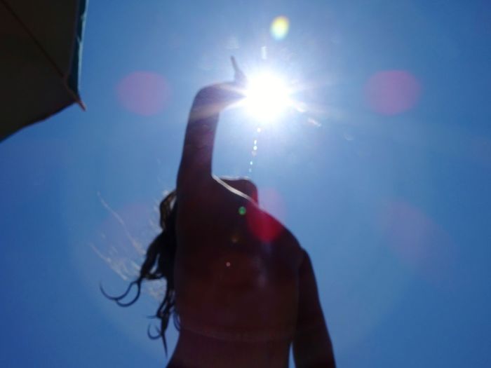 Midsection of woman holding sun against sky