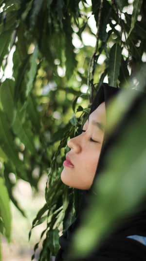 Close-up of woman with eyes closed by plants