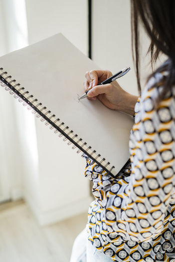 Female professional drawing in spiral notebook
