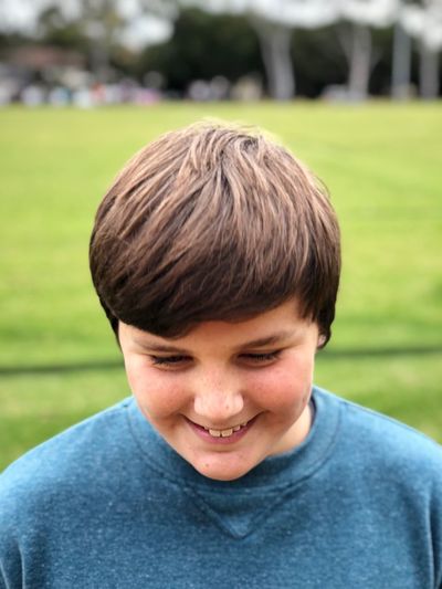 Close-up of boy smiling while standing at park