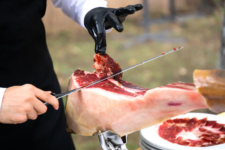 Ham cutter with gloves at a party cutting thin slices of iberian ham