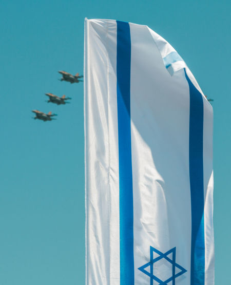 Airplanes performing airshow with israeli flag in foreground during independence day