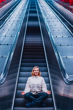 Woman meditating while sitting on escalator