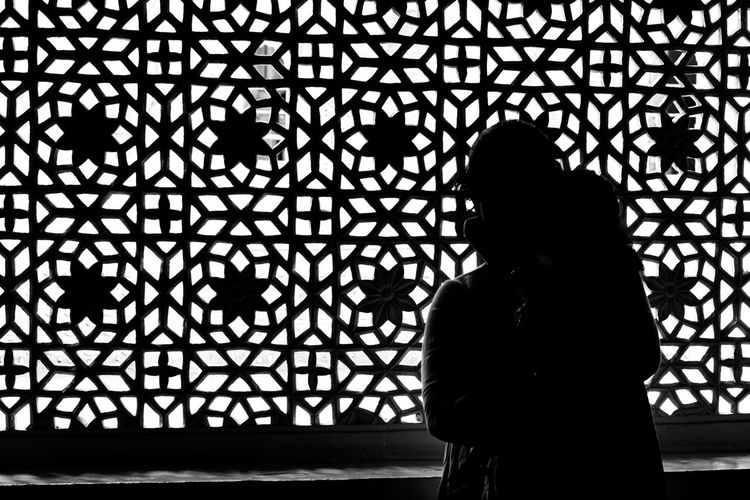 Silhouette woman standing against window