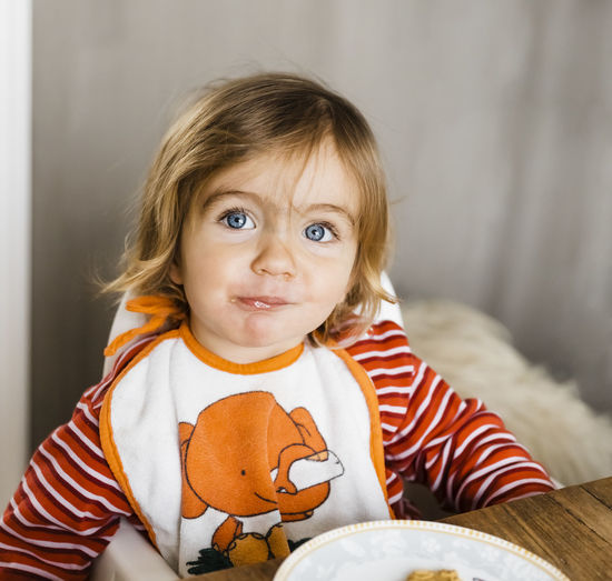 Close-up of cute baby girl eating at home