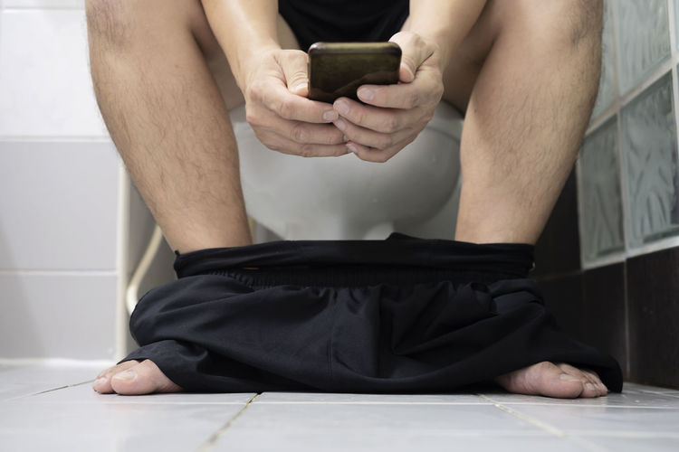 Low section of man using mobile phone