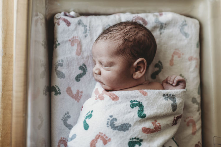 Overhead view of newborn boy swaddled in hospital bassinet