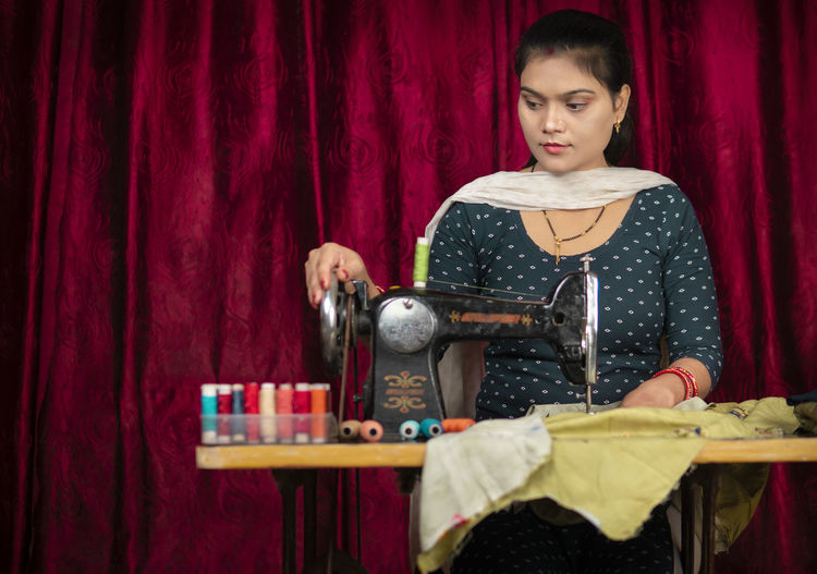 Portrait of young woman using sewing machine