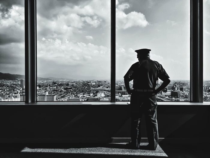 Rear view of policeman looking at cityscape through window