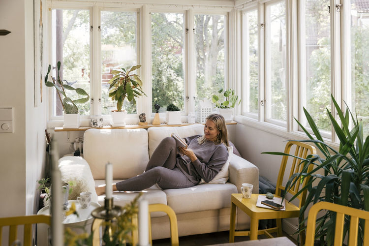 Businesswoman with book reclining on sofa in living room at home
