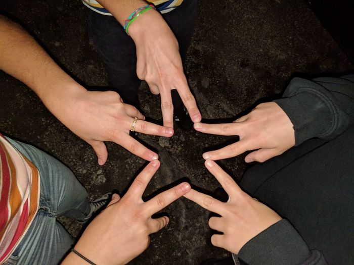 High angle view of friends forming star shape with fingers