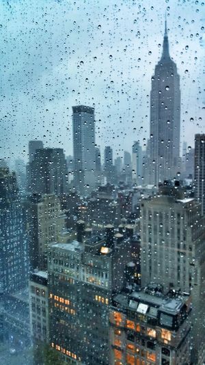 View of cityscape through wet window during rainy season