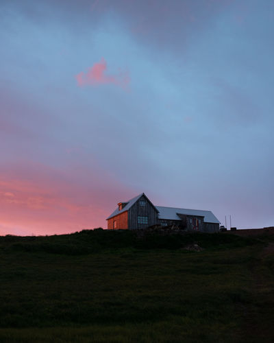 Low angle view of house on field against sky during sunset