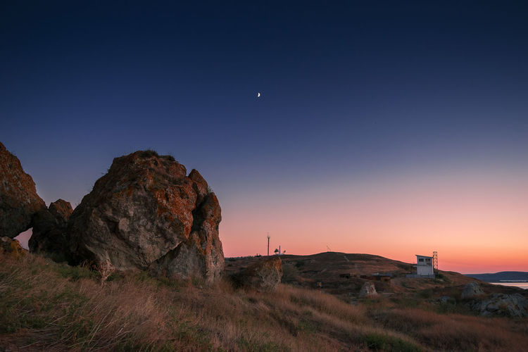 Scenic view of rocks against clear sky at sunset