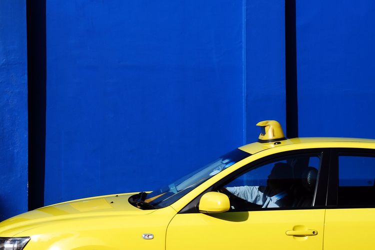 Yellow taxi by blue wall