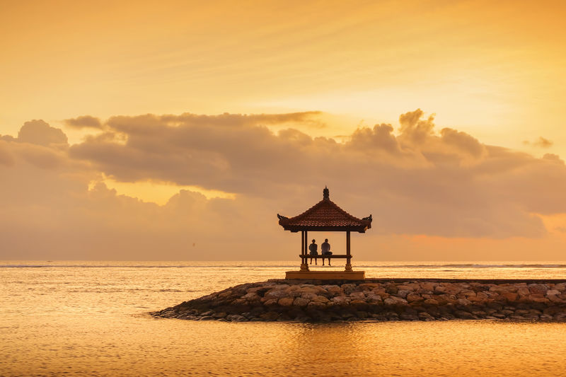 Lifeguard hut on beach against sky during sunset