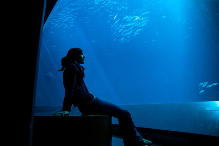 Woman sitting in aquarium 