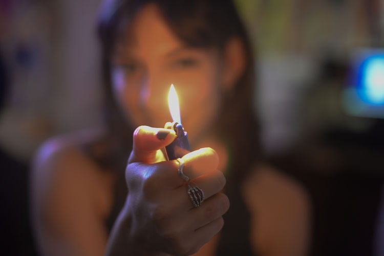Close-up of woman igniting cigarette lighter at home