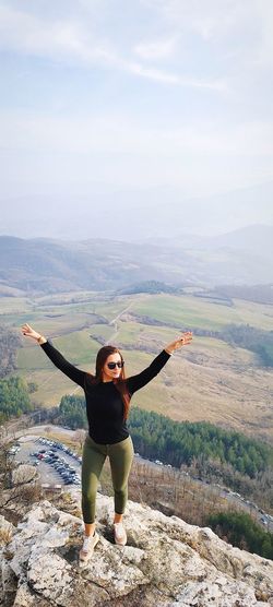 Full length of woman with arms raised on mountain against sky