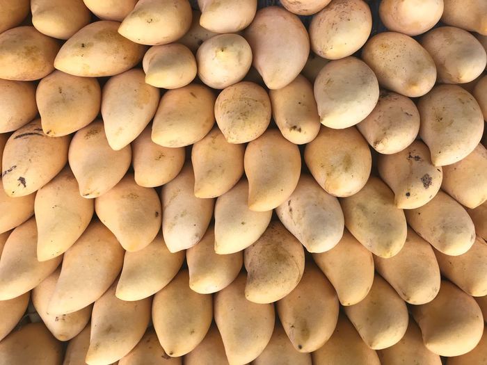 Full-frame shot of ripe gold barracuda mangoes in daylight local market
