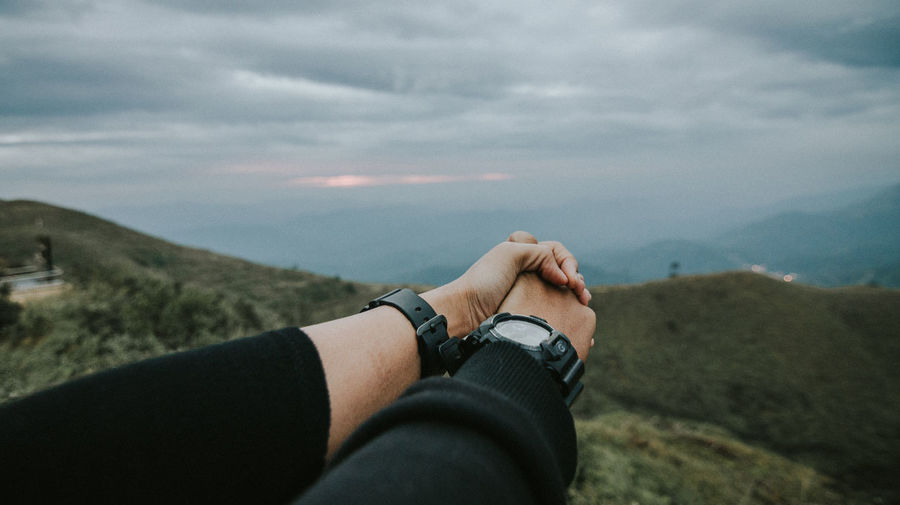 Couple holding hands against sky