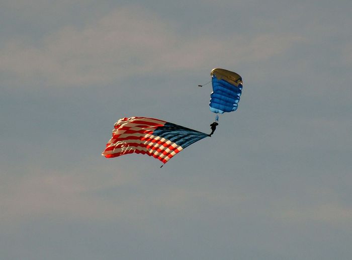 Low angle view of paraglider flying with american flag against sky
