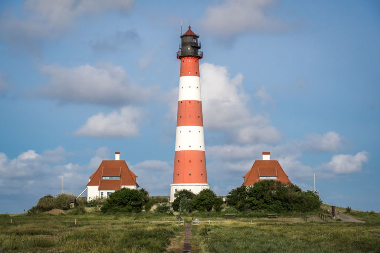 Lighthouse by building against sky