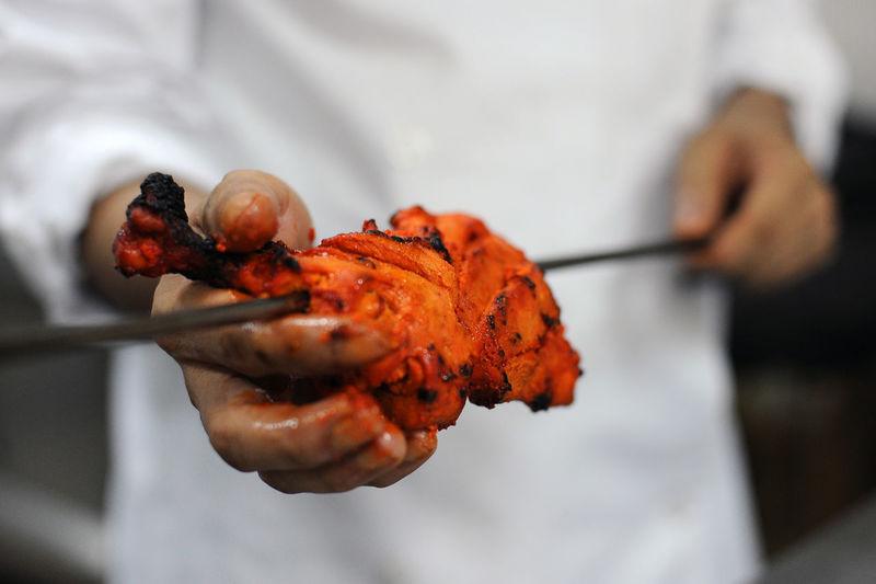 Cook preparing chicken in curry and spices