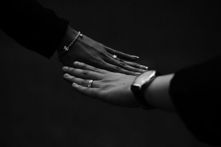 Close-up of couple hands against black background