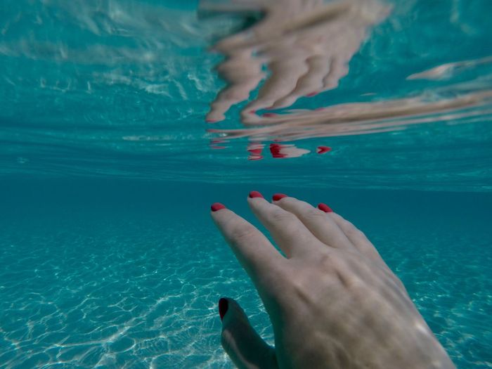Cropped image of woman gesturing underwater in swimming pool