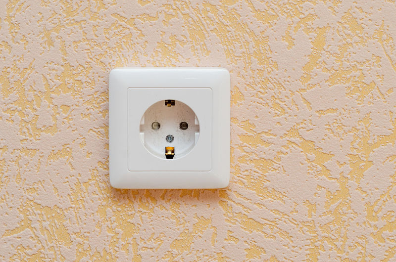Euro socket on the wall with yellow wallpaper