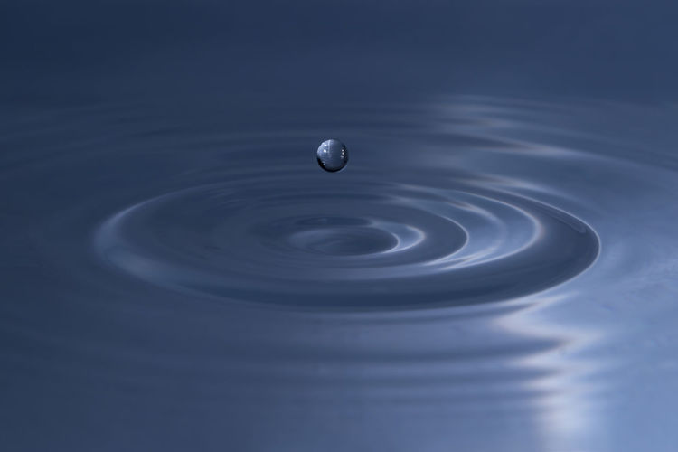 Close-up of water drop above wavy surface