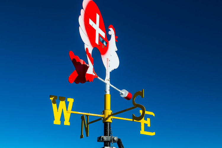 Low angle view of weather vane against blue sky.view from klein matterhorn, swiss alps