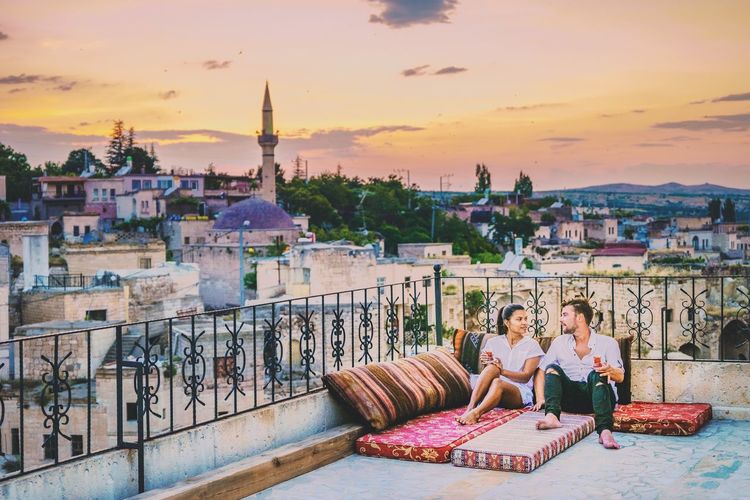 Couple sitting on mattresses in city during sunset