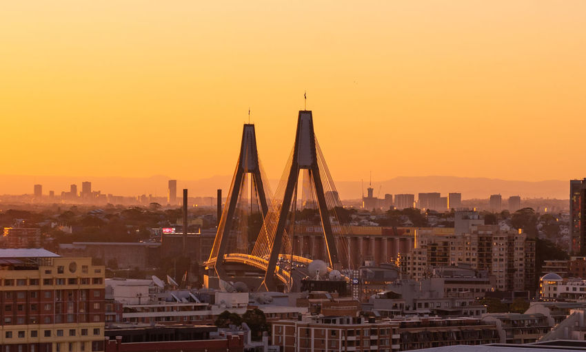 Modern bridge in city against sky during sunset