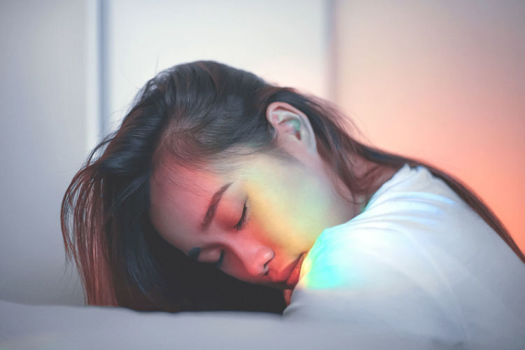 Side view of prism light falling on young woman