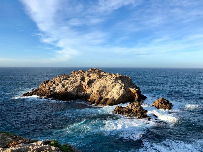 Rock formation in sea against sky