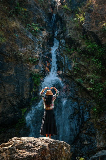 Woman standing on a rock with a waterfall