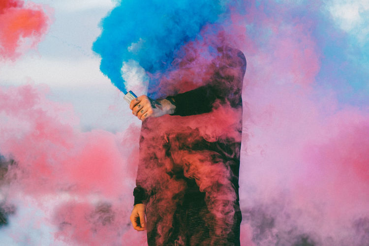 Midsection of man in multi colored smoke
