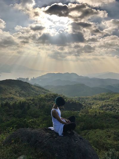 Man sitting on landscape against mountains