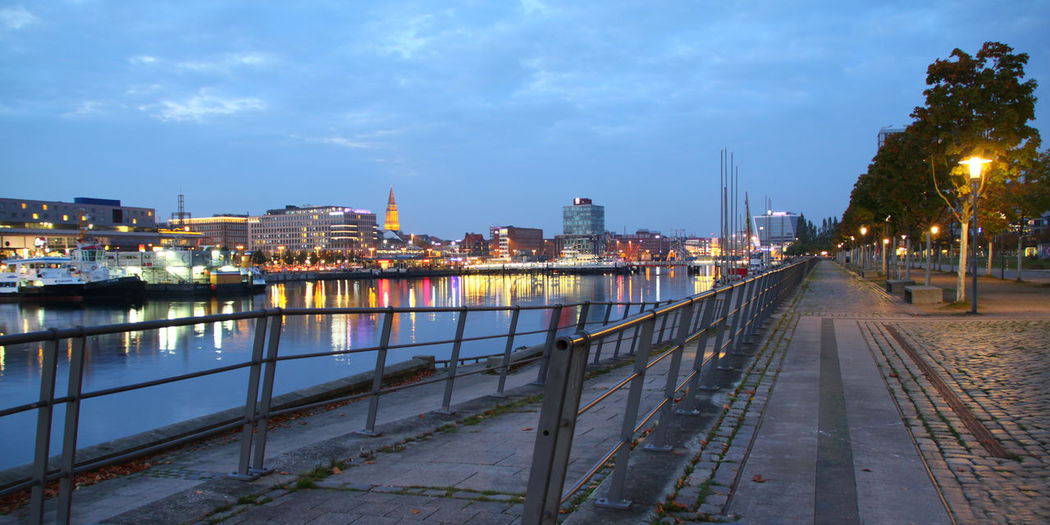 Illuminated bridge over river against sky in city