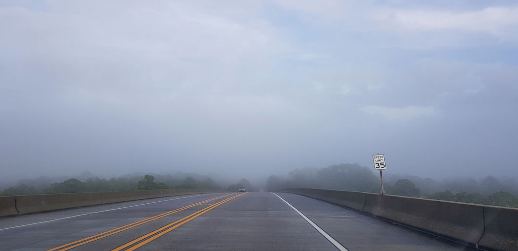Empty road against foggy sky