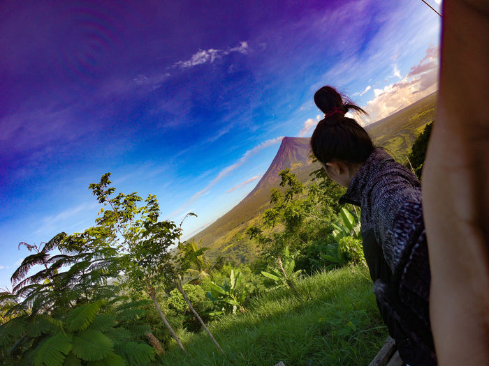 Side view of woman standing against mountain and sky