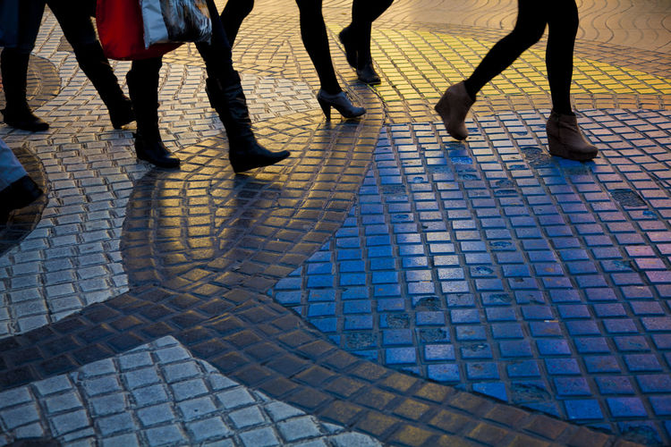 Low section of people walking on cobblestone