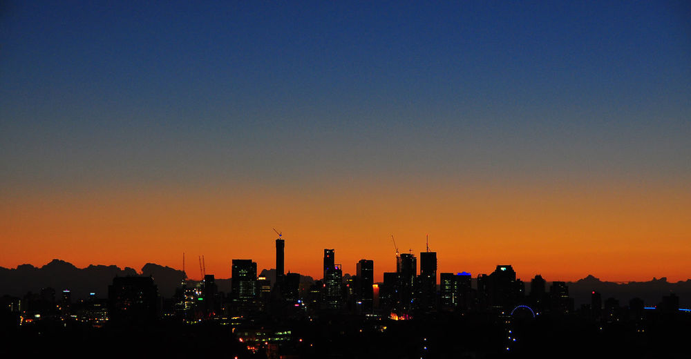 Silhouette buildings against clear sky during sunset